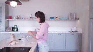 A hot chick is cooking and stripping in a kitchen, showcasing her allure