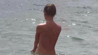 A group of nudists have fun on the beach without any clothes
