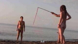 Nude beauty plays on the beach, exposing her body to sun and wind