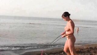Nude beauty plays on the beach, exposing her body to sun and wind