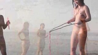 Nude beauty plays on the beach, exposing her body to sun and wind