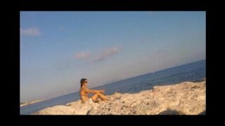 A young girl is basking in the sun completely naked on the beach