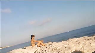 A young girl is basking in the sun completely naked on the beach