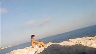 A young girl is basking in the sun completely naked on the beach